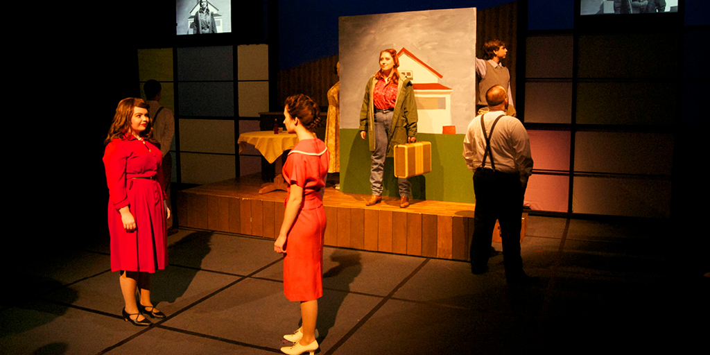 Theate image of two women talking and three people in the background